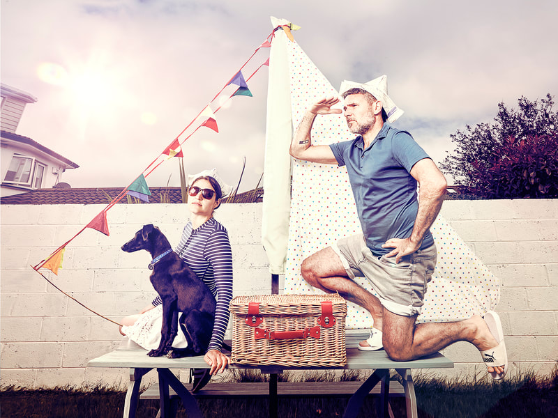 Fashion photography with a couple and a dog playing in a garden table as it was a sailboat with commercial photography aesthetics and vibrant colours