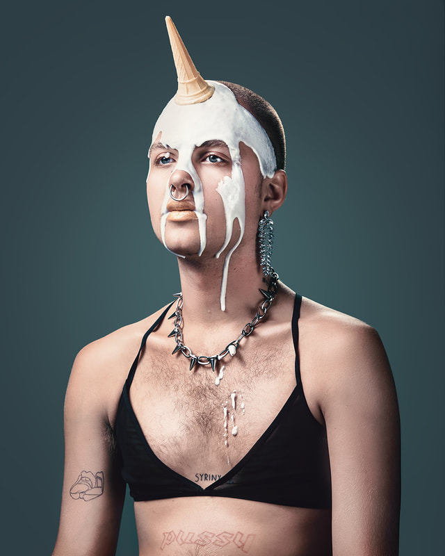 unicorn created with and ice cream cone over a young male model shot in studio with grey background 