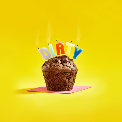 high quality Muffin photographed in studio with candles forming the word dirty in vibrant colours 