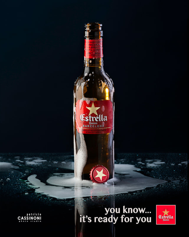 bottle of estrella beer shoot in photo studio over a reflective dark surface 