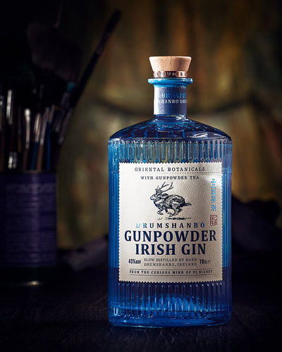 Blue bottle of Gunpowder Irish Gin photographed in front of a yellow canvas in a photo studio