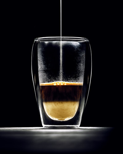 Glass of coffee with condense mils photographed in studio with dramatic lighting