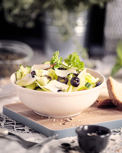 salad in a bowl with green lettuce , black olives and parmesan photographed on set for food magazine in dublin