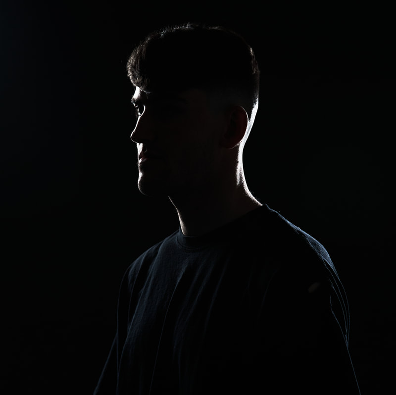 backlit image of a young male define for two bins of light coming from the side shoot on a black background in a photo studio
