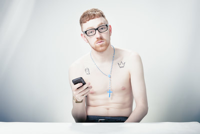 portrait of famous artist Mango holding a cellphone in a photo studio in topples wearing glasses 